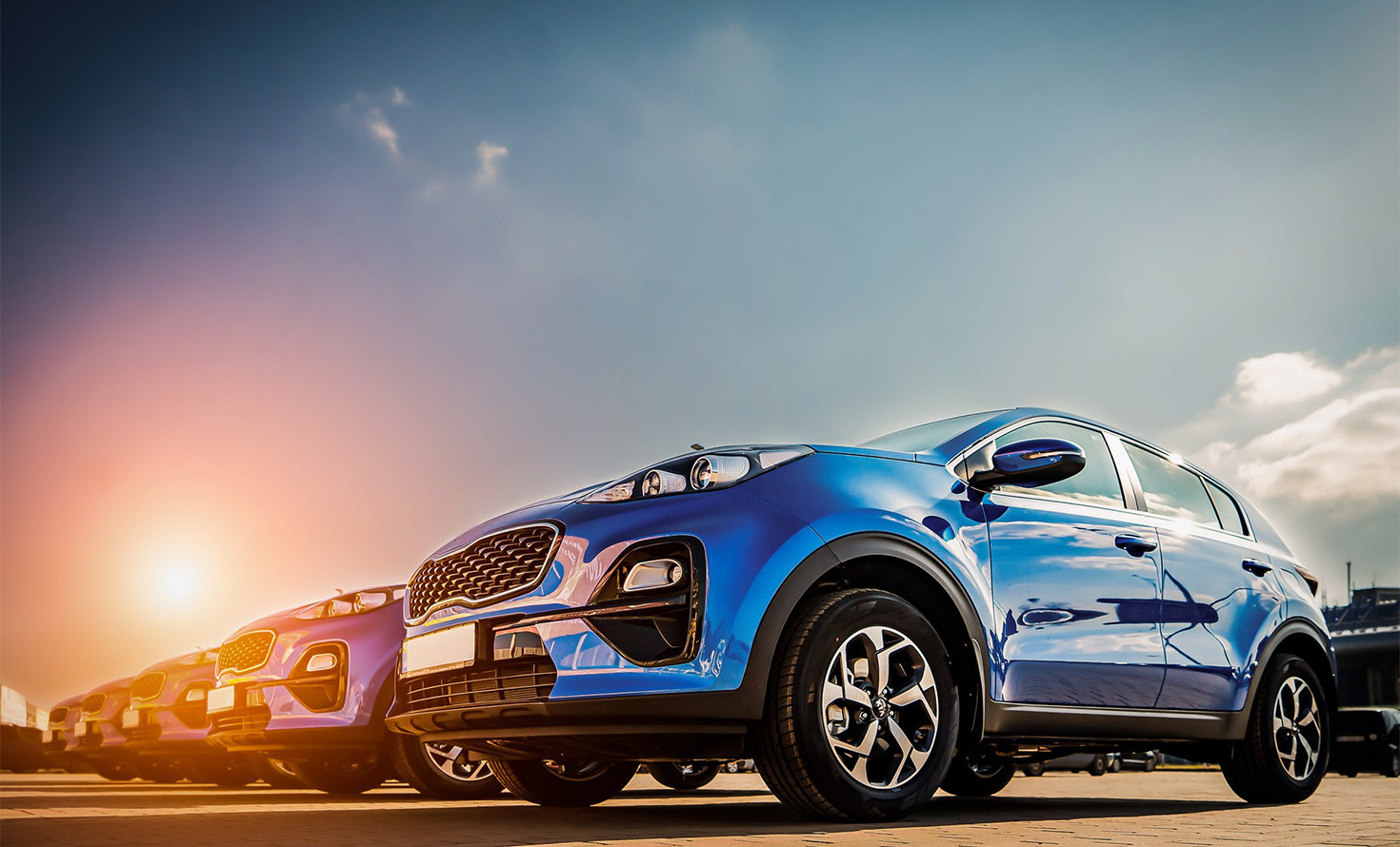 Blue SUV parked with sun setting in the background, highlighting sleek design and modern wheels.