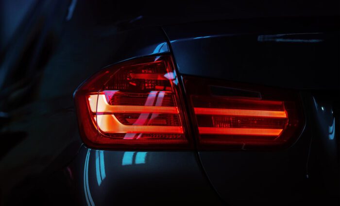 Red car tail light glowing in the dark, showcasing sleek design and modern technology.